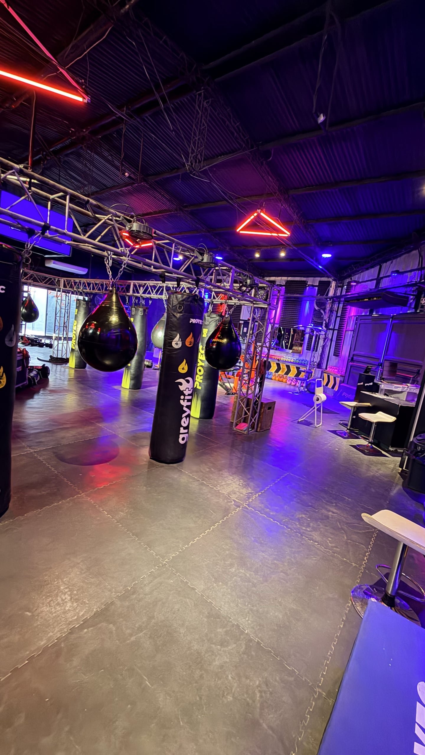 Bolsas de boxeo bajo la estructura de truss con luces rojas y violetas