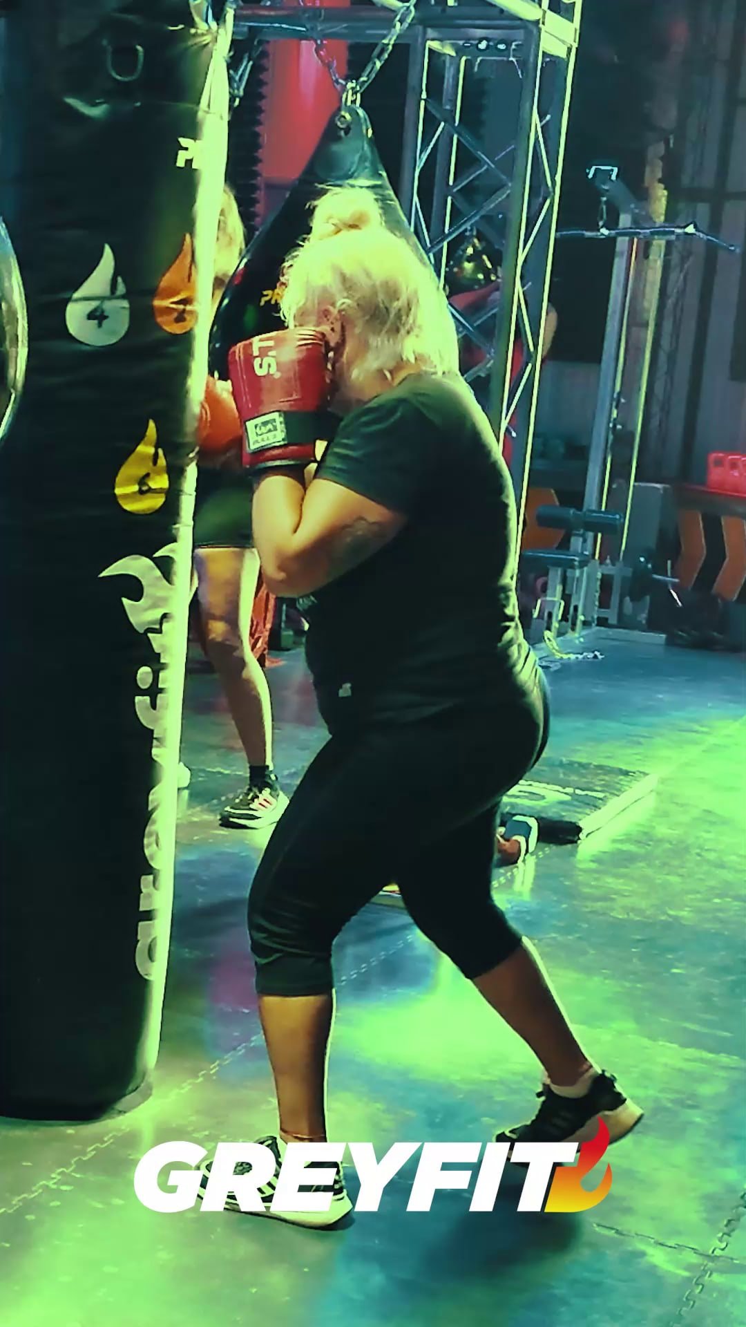 Alumna con guantes rojos golpeando la bolsa en la jaula de Fitbox